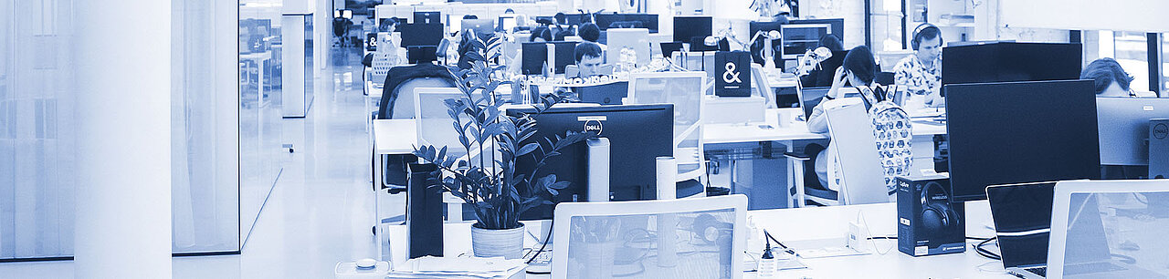 Ein Großraumbüro mit mehreren Arbeitern, die konzentriert an ihren Schreibtischen arbeiten