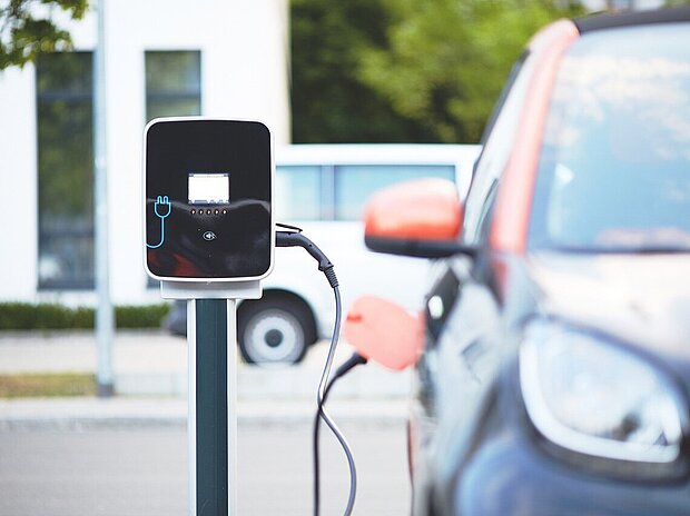 Eine Ladestation wird von einem schwarz-orangenen Elektroauto genutzt