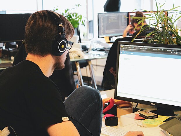 Ein Mann arbeitet mit einem Headset an seinem Arbeitsplatz