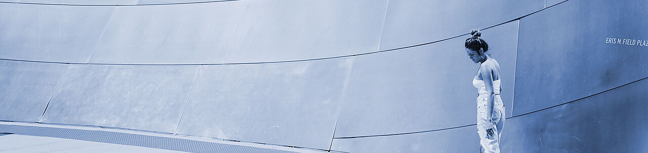 Eine in Weiß gekleidete Frau vor einer grauen Wand