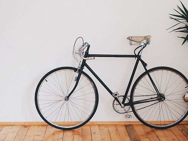 Ein schwarzes Fahrrad mit beigem Sitz, angelehnt an eine weiße Wand
