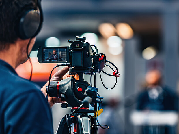 Ein Kameramann dreht eine Aufnahme von einem Mann