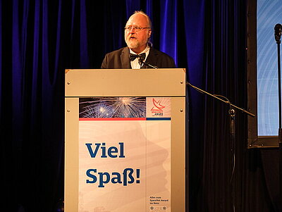 Ein Mann im Anzug hält eine Rede auf einer Bühne