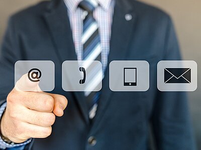 Vier eingeblendete Symbole vor einer im Anzug gekleideten Person