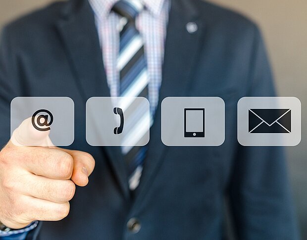 Vier eingeblendete Symbole vor einer im Anzug gekleideten Person