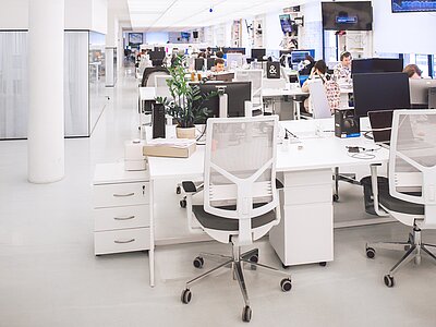 Ein hell erleuchteter, großzügiger Büroraum mit mehreren Personen bei der Arbeit