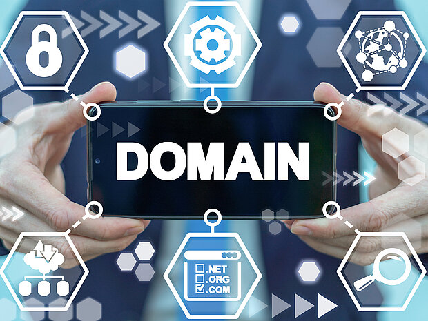 Ein geschäftig gekleideter Mann präsentiert ein Smartphone mit der Beschriftung 'Domain' im Hintergrund. Auf dem Bildschirm sind zahlreiche Zweigungen zu sehen, die eine Vielzahl von Dienstleistungen repräsentieren