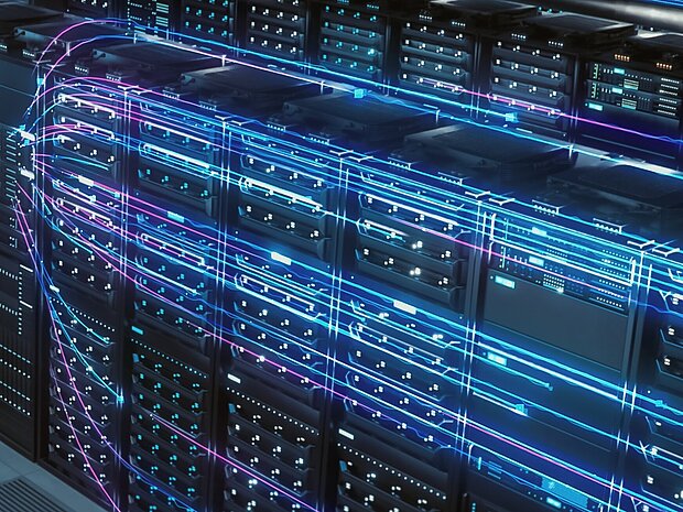 Blick von einer erhöhten position auf einen Serverraum. Zusehen sind mehreren Reihen an blau leuchtenden Server-Schränken.