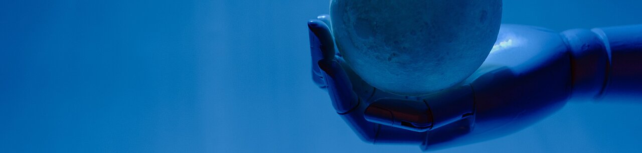 Eine Roboterhand hält eine Kugel vor einem hellblauen Hintergrund.