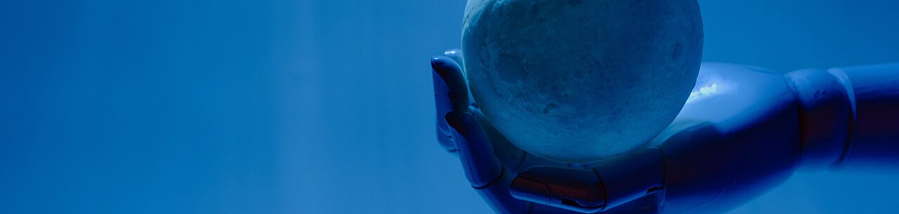 Eine Roboterhand hält eine Kugel vor einem hellblauen Hintergrund.