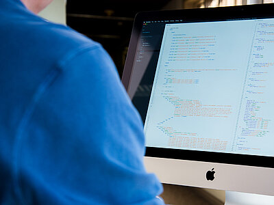 Bildschirm mit mehreren angezeigten Daten wird von Person in blauen T-Shirt benutzt