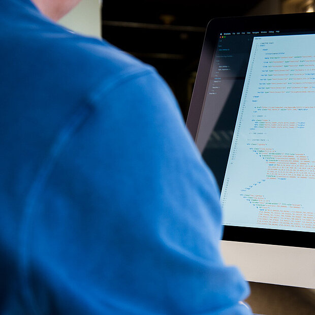 Bildschirm mit mehreren angezeigten Daten wird von Person in blauen T-Shirt benutzt