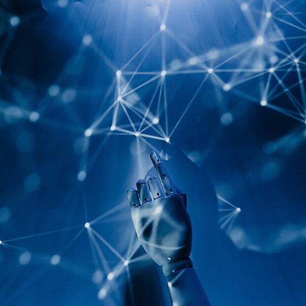 Eine Roboterhand berührt einen Bildschirm mit weißen Linien, die Vernetzung darstellen