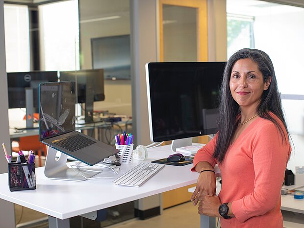 Eine Frau mit einem Laptop und einem Bildschirm an ihrem Arbeitsplatz im Büro
